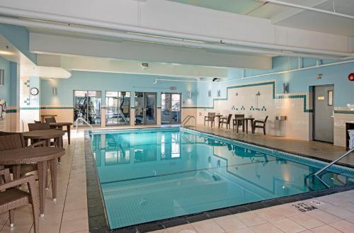 a large swimming pool in a building with tables and chairs at Holiday Inn Express Kamloops by IHG in Kamloops