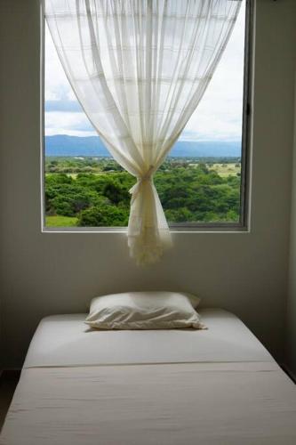 a window with a curtain and a bed in a room at El descanso que mereces,es aquí. in Girardot
