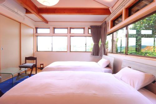two beds in a room with two windows at 二尊院宿坊えんとき in Nagato