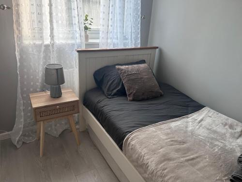 a small bed with a night stand next to a window at HavilaHome Retreat in Manchester