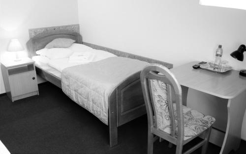a bedroom with a bed and a desk and a chair at Hotel Dukat in Biała Podlaska