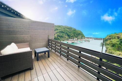 a balcony with a bench and a view of a river at 鵜原館 -Ubarakan- in Katsuura