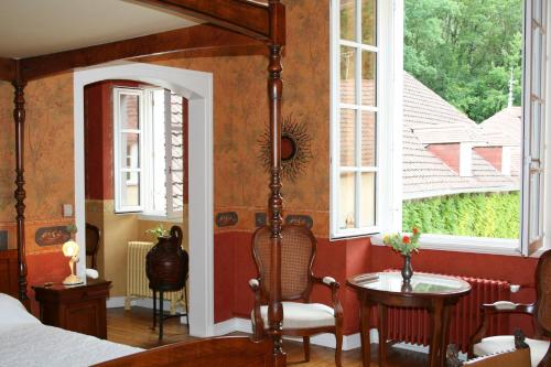 a bedroom with a bed and a table and windows at Manoir De Montflambert in Mutigny