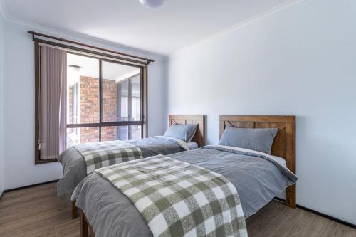 two beds in a room with a window at Bayt Baytak in Sussex inlet