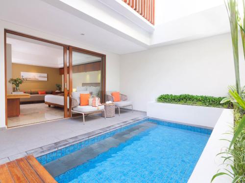 a villa with a swimming pool and a living room at The Magani Hotel and Spa in Legian