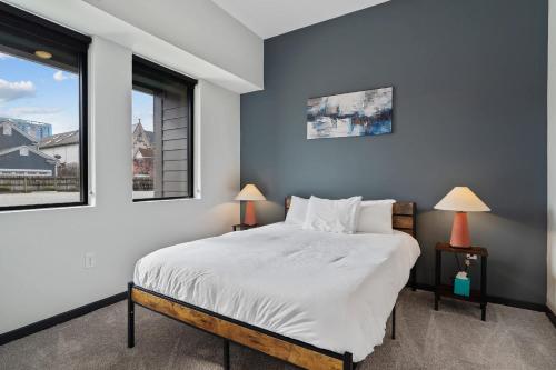 a bedroom with a large bed and two windows at CozySuites Mass with parking lounge & roof deck #23 in Indianapolis