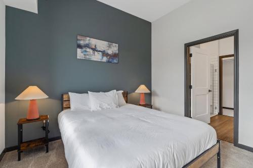 a bedroom with a large white bed and two lamps at CozySuites Mass with parking lounge & roof deck #23 in Indianapolis