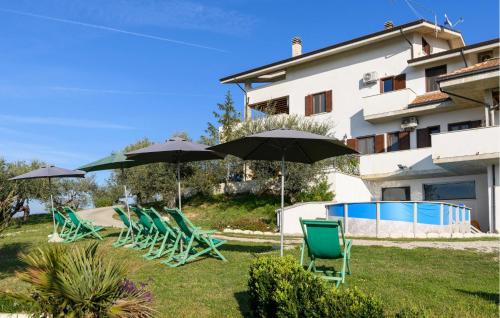 eine Gruppe von Liegestühlen und Sonnenschirmen neben einem Gebäude in der Unterkunft Beautiful Apartment In Moscufo in Moscufo