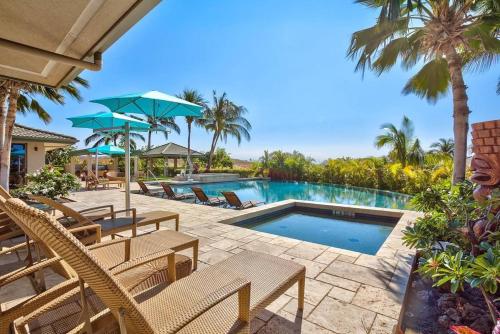 a swimming pool with chairs and umbrellas at ❤PiH❤ Beautiful Ocean Villa Nani Moana Hale Stunning Ocean Views in Hapuna Beach