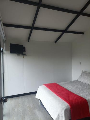 a white bedroom with a bed with a red blanket at LA ESTANCIA DE FRANCIA Paipa in La Bolsa