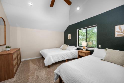 a bedroom with two beds and a green accent wall at Woodlands Area Lake View Retreat in Conroe