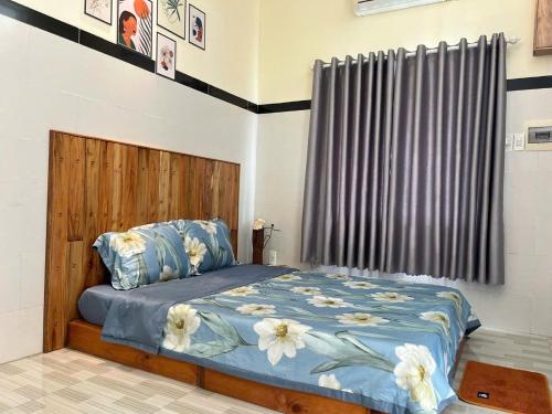 a bedroom with a bed with blue comforter and flowers on it at Đại Dương La Gi Homestay & Coffee in La Gi