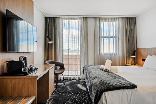 a hotel room with a bed and a desk at Prince of Wales Hotel in Hobart