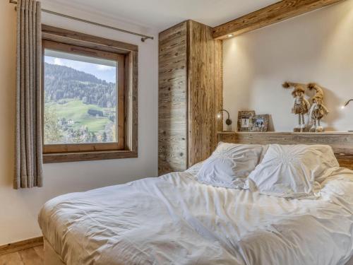 une chambre avec un grand lit avec une fenêtre dans l'établissement Appartement rénové 2 pièces à Megève avec balcon, wifi, parking. - FR-1-453-319, à Megève