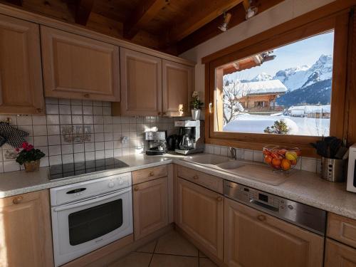 une cuisine avec vue sur une montagne enneigée dans l'établissement Chalet spacieux 10 pers. près pistes ski, parking privé - FR-1-467-135, au Grand-Bornand