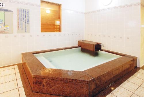 a large bath tub in a bathroom with a mirror at Tsurugi Koizuki in Kamiichi