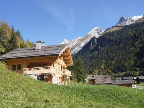 une cabane en rondins sur une colline avec des montagnes en arrière-plan dans l'établissement Charmant chalet 4 pers avec cheminée au Grand-Bornand - FR-1-467-137, au Grand-Bornand