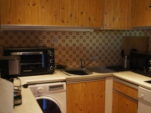 une cuisine avec un évier et un micro-ondes dans l'établissement Charmant appartement près des pistes, parking inclus - FR-1-467-138, au Grand-Bornand