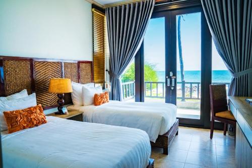 two beds in a room with a view of the ocean at Lotus Muine Resort & Spa in Mui Ne