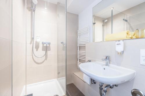 a white bathroom with a sink and a shower at Candlewood Suites Fürth by IHG in Fürth