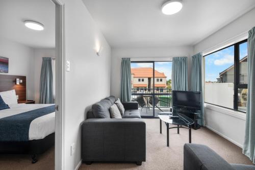 a bedroom with a bed and a couch and a tv at Panorama Motor Lodge in Timaru