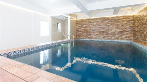 a swimming pool in a room with a brick wall at RedDoorz Plus near Tambo Paranaque in Manila