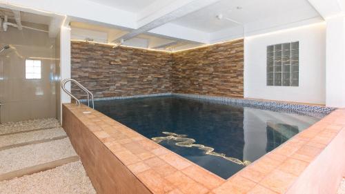 a swimming pool in a house with a brick wall at RedDoorz Plus near Tambo Paranaque in Manila