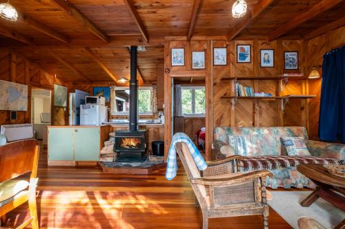 a living room with a fireplace in a log cabin at Quintessential kiwi kuratau bach in Kuratau