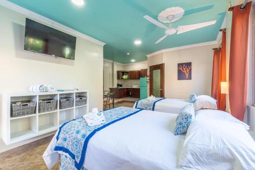 a bedroom with two beds and a flat screen tv at Island Magic Beach Resort in Caye Caulker
