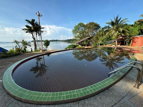 a swimming pool next to a body of water at Koh Mak Buri Hut Natural Resort in Ko Mak