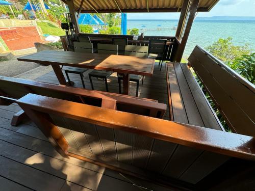 a restaurant with wooden tables and chairs and the ocean at Koh Mak Buri Hut Natural Resort in Ko Mak
