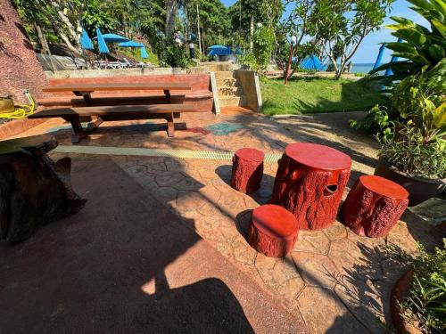 a picnic table and a bench and some logs at Koh Mak Buri Hut Natural Resort in Ko Mak