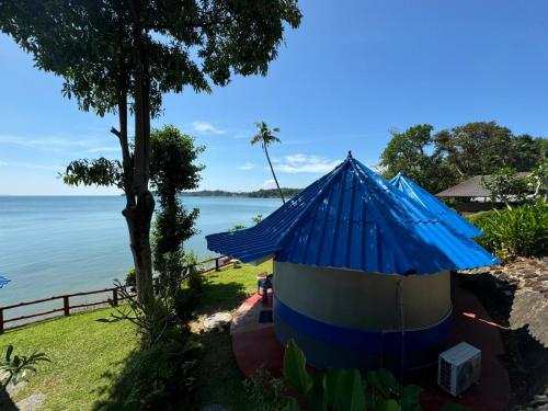 a blue and white hut next to the water at Koh Mak Buri Hut Natural Resort in Ko Mak