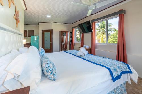 a bedroom with a large white bed and a window at Island Magic Beach Resort in Caye Caulker
