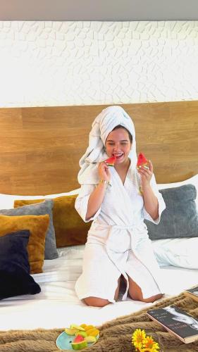 a woman sitting on a bed holding two pieces of fruit at Mantra Hotel Boutique in Santa Marta