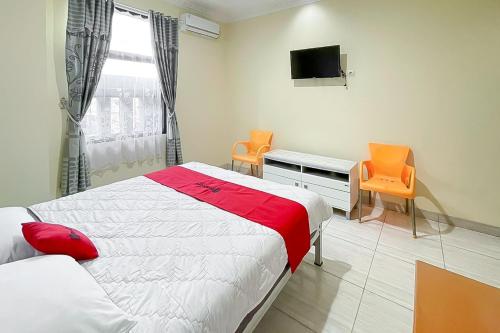 a bedroom with a bed and a desk and a tv at RedDoorz near Grage Mall Cirebon in Cirebon