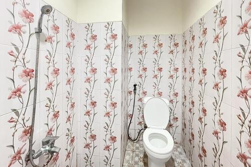 a bathroom with a toilet and flowers on the wall at RedDoorz near Grage Mall Cirebon in Cirebon