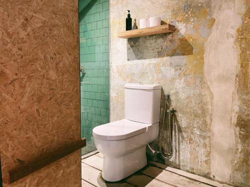 a bathroom with a toilet and a green wall at Belakang Kong Heng Ipoh Hotel in Ipoh