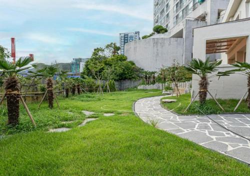 a garden with palm trees and a walkway at Geoje Hound Hotel & Spa in Geoje 