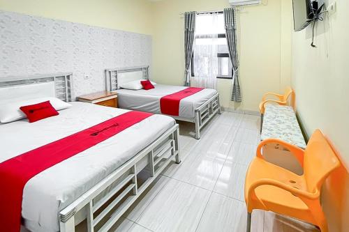 a hotel room with two beds and a chair at RedDoorz near Grage Mall Cirebon in Cirebon