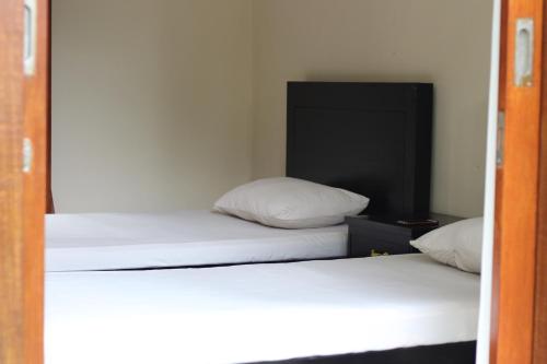 two beds in a room with white sheets and pillows at Arnata Guest House & Pasraman Yoga Lokanata in Bangli