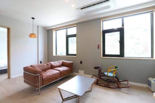 a living room with a leather couch and a table at Geoje Hound Hotel & Spa in Geoje 