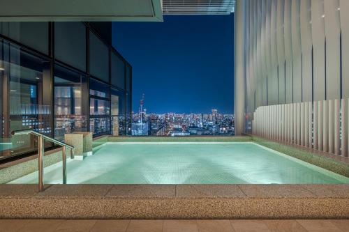 a swimming pool in a building with a view of a city at Candeo Hotels Osaka The Tower in Osaka