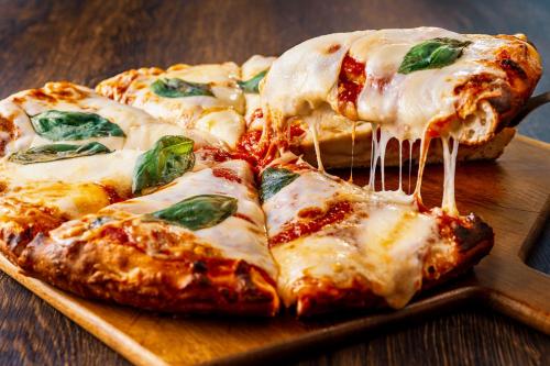 a pizza sitting on top of a wooden cutting board at Candeo Hotels Osaka The Tower in Osaka