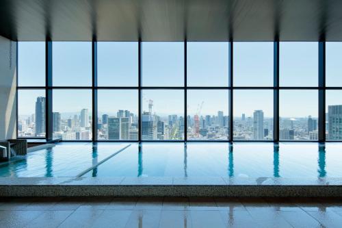 a pool in a building with a view of a city at Candeo Hotels Osaka The Tower in Osaka