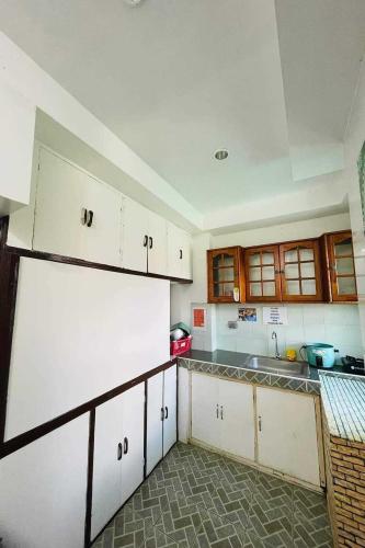 a kitchen with white cabinets and a white refrigerator at Istroberi Inn Palawan near Airport in Puerto Princesa City