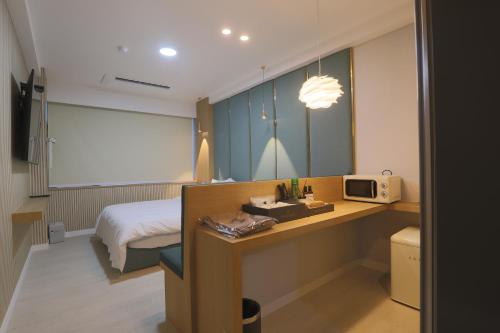 a bedroom with a bed and a desk with a microwave at Geoje Hound Hotel & Spa in Geoje 