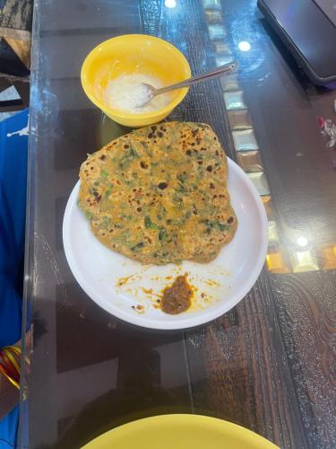 a white plate with a piece of food on a table at VMP Villa Home Stay in Tājganj