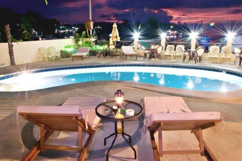 a pool at night with chairs and a table at Oriental Hill Sabang Resort Puerto Galera in Puerto Galera