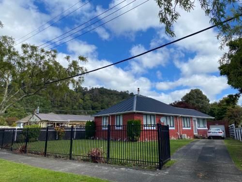 une maison rouge avec une clôture noire devant elle dans l'établissement Pet friendly house with hot tub, à Lower Hutt